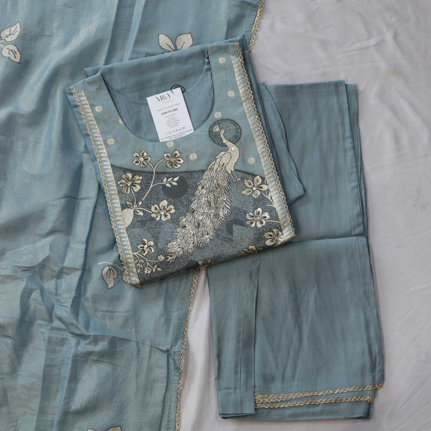 Teal embroidered fabric with a peacock design
