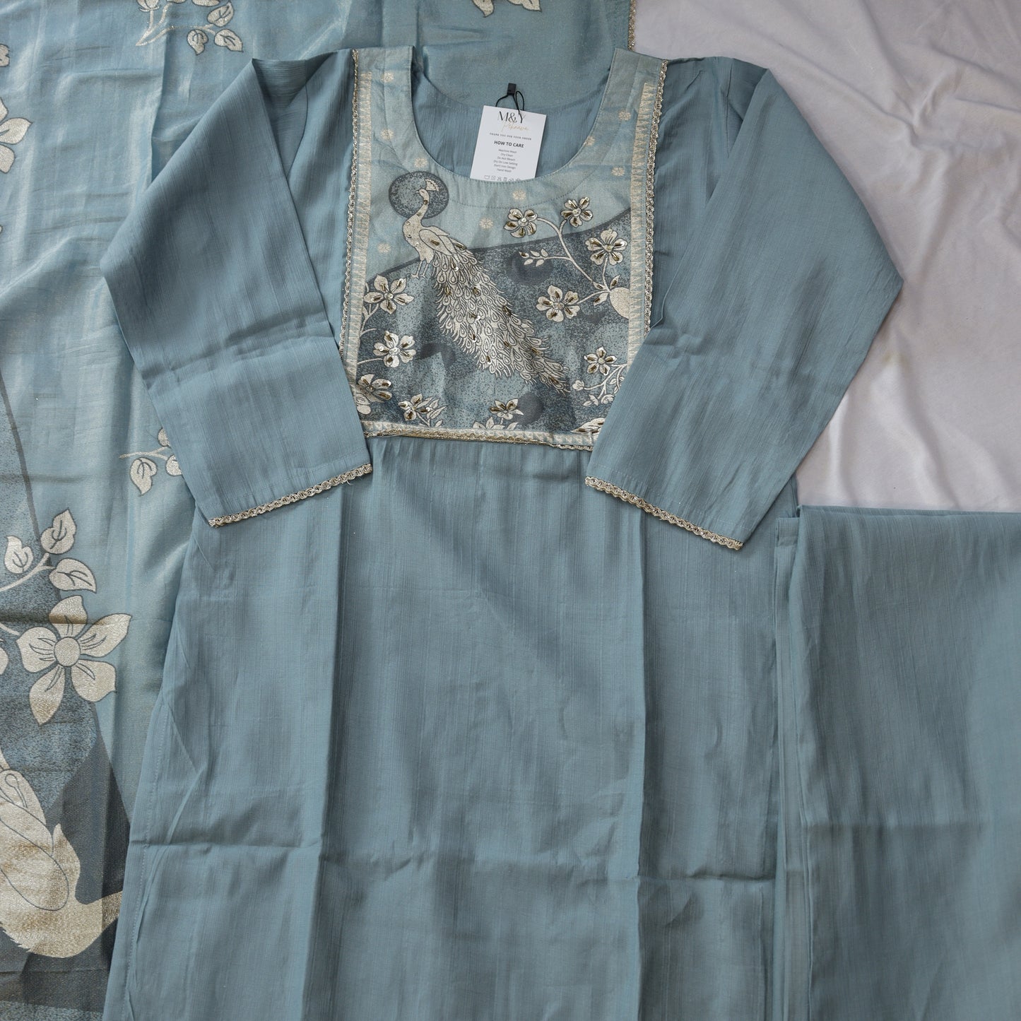 Teal embroidered fabric with a peacock design