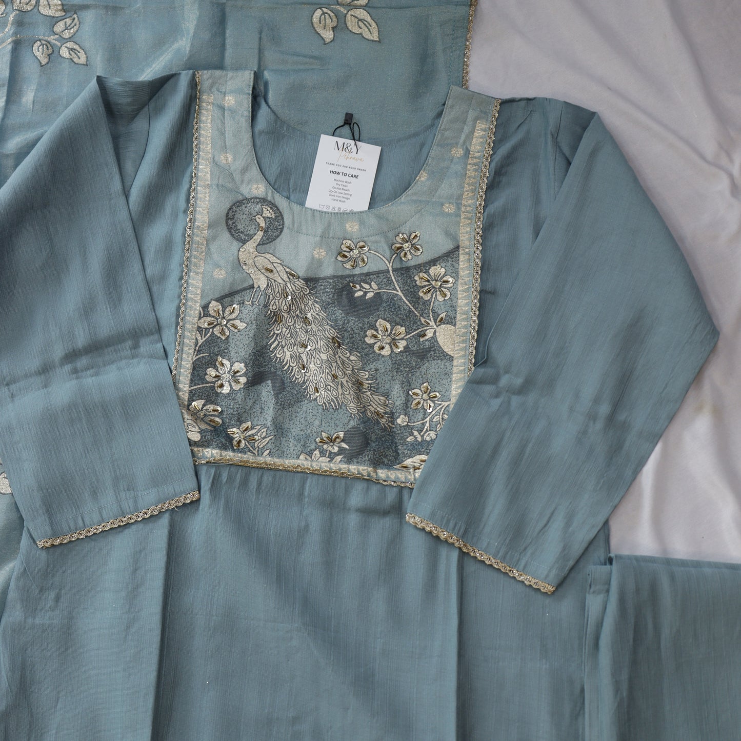 Teal embroidered fabric with a peacock design