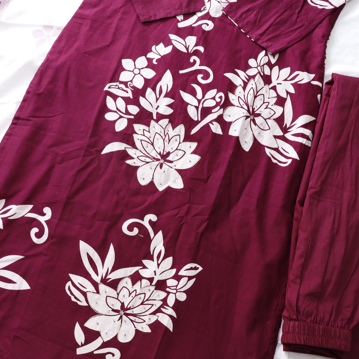 Maroon fabric with white floral patterns on a white background