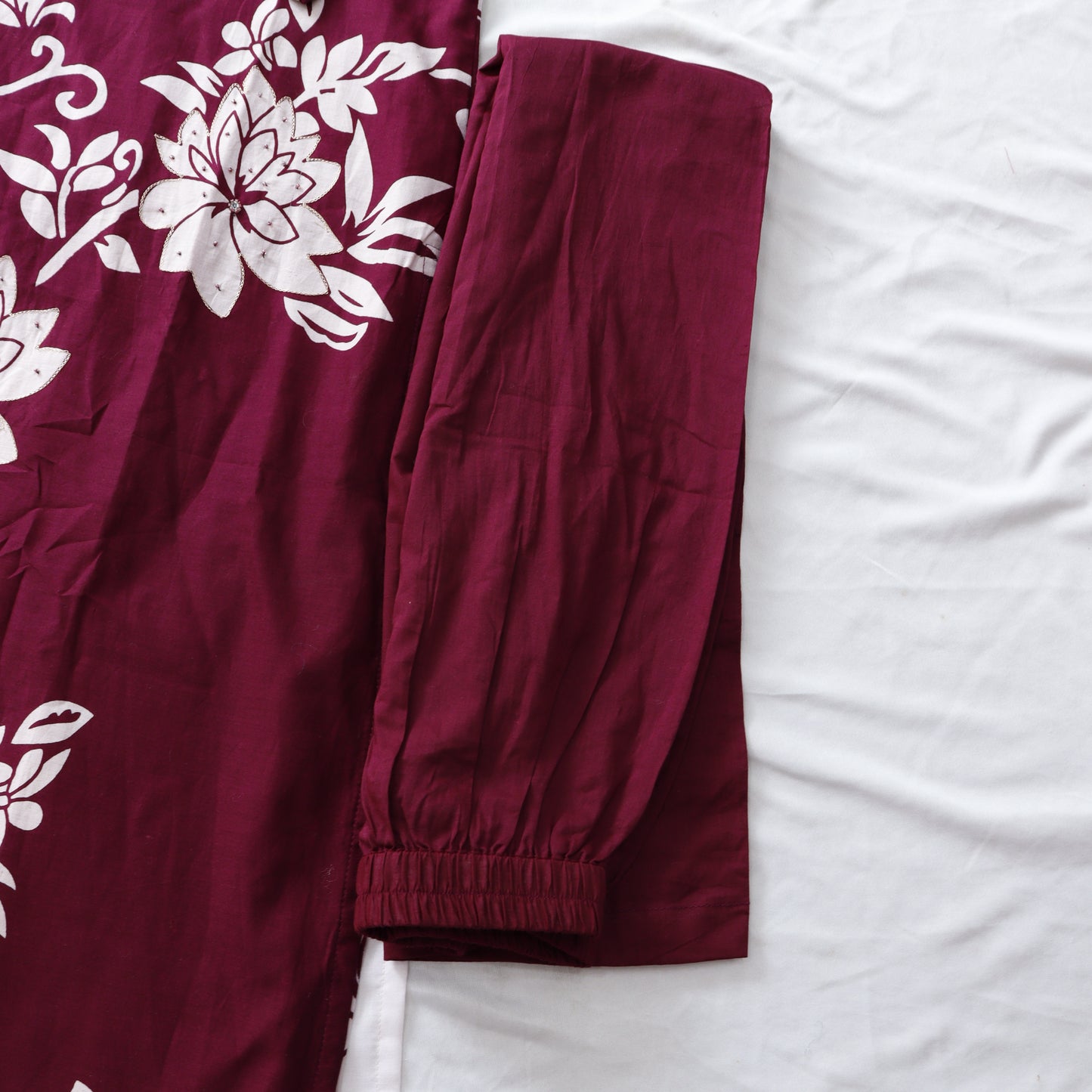 Maroon pants with white floral patterns on a white background