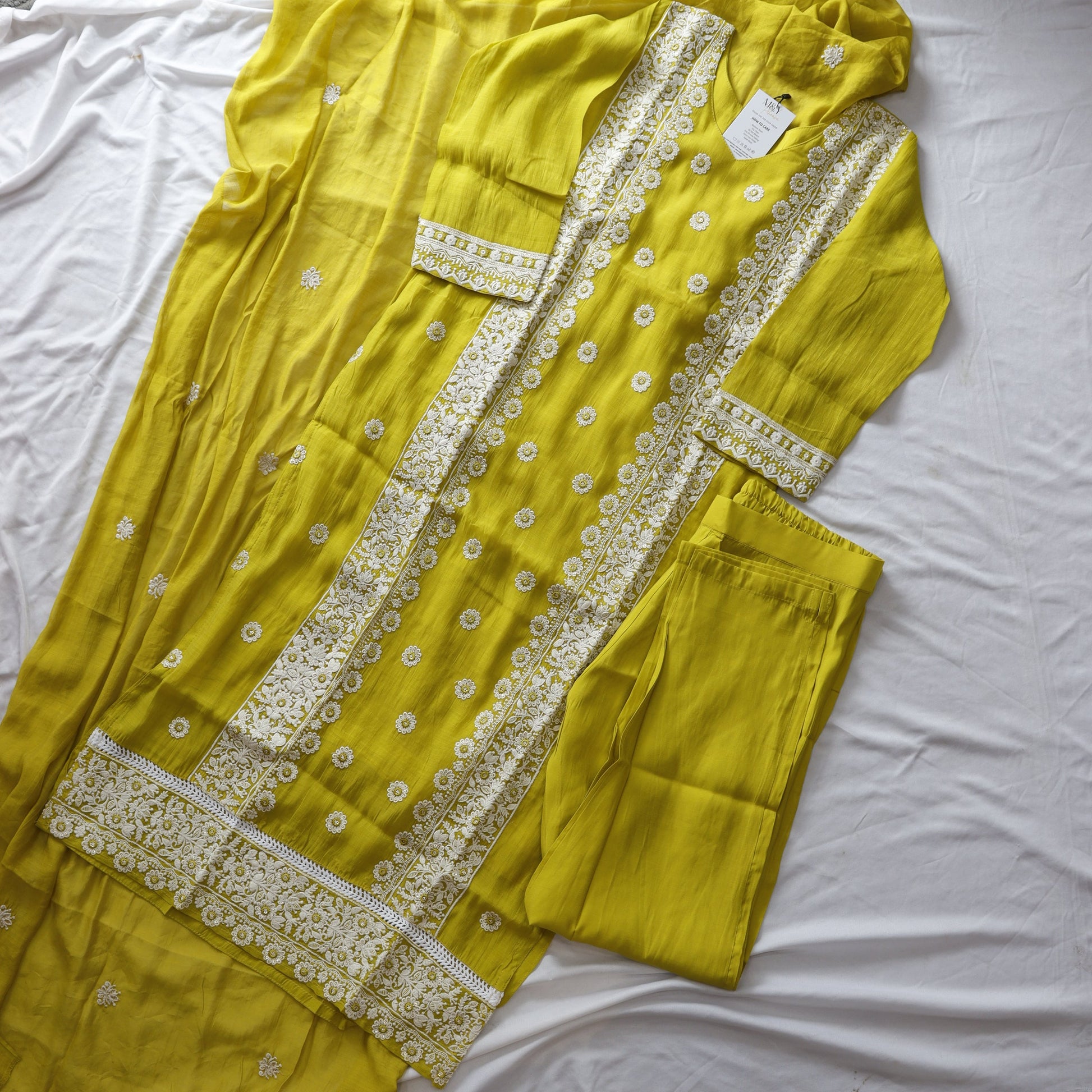Yellow saree with white embroidery on a white background