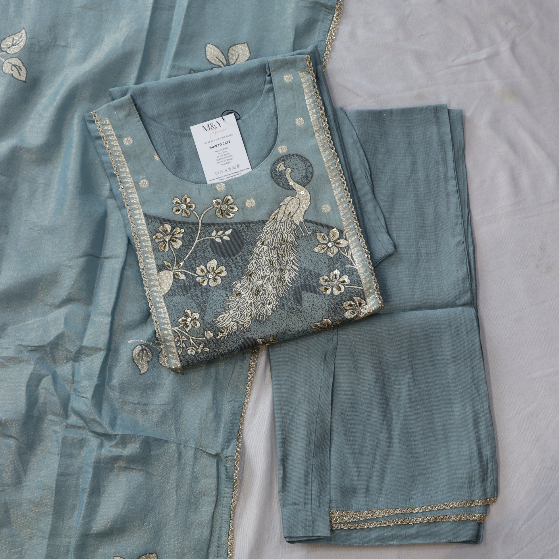 Teal embroidered fabric with a peacock design