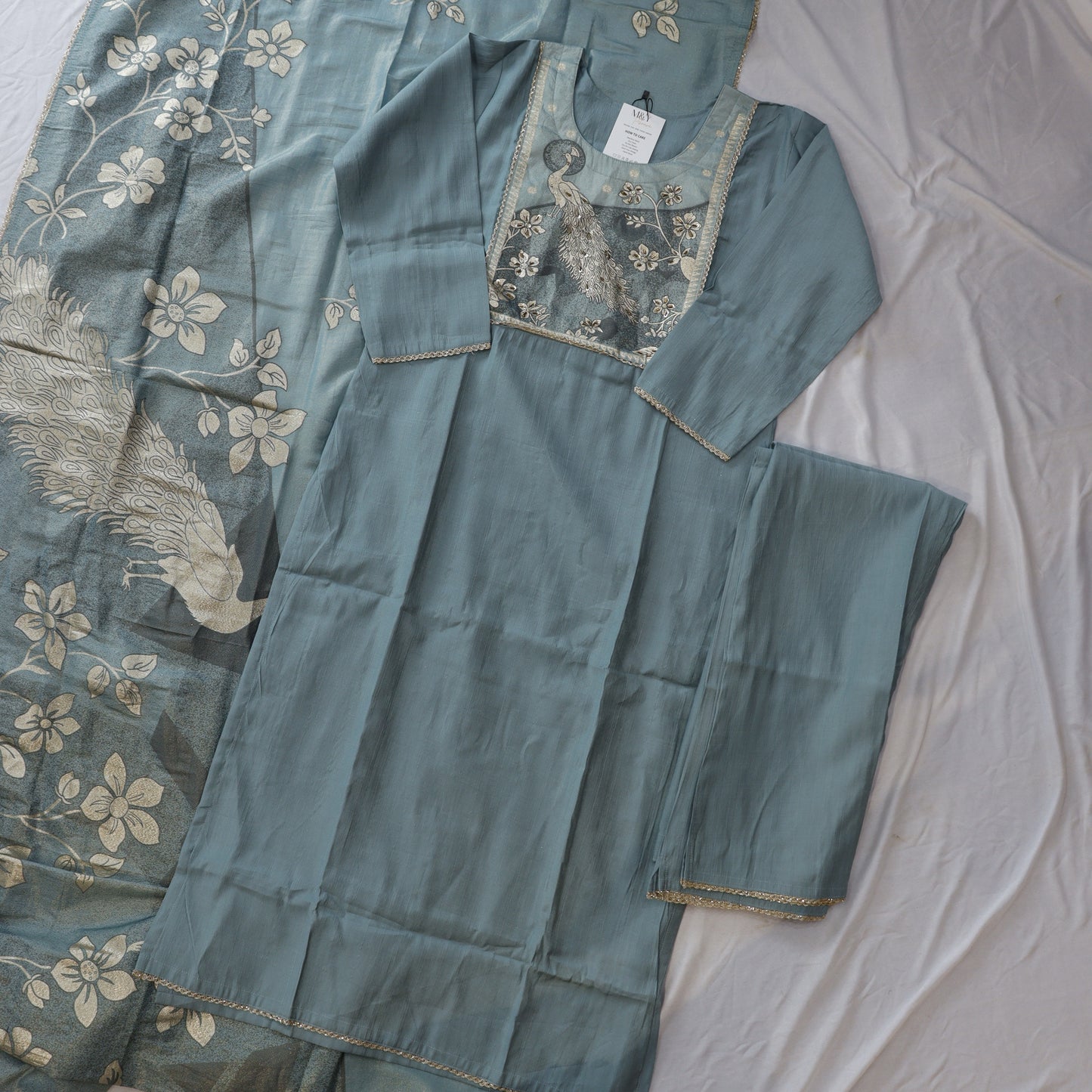 Teal embroidered fabric with a peacock design