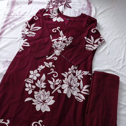 Maroon pajama set with white floral patterns on a white bedspread.